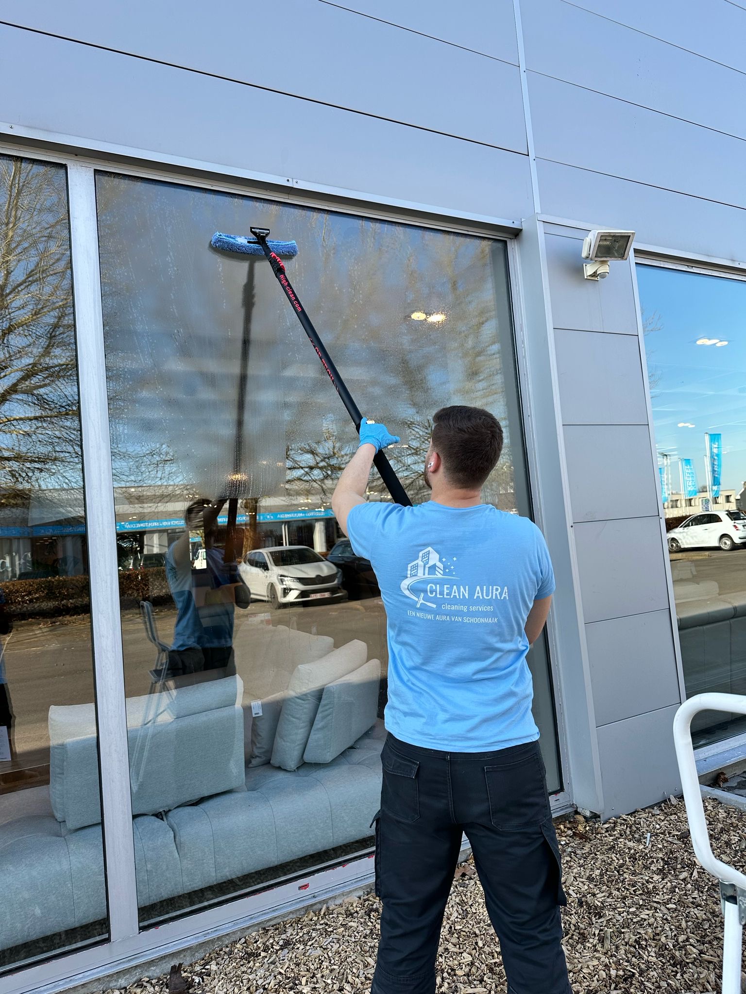Clean Aura medewerker wast een hoge showroomruit met telescopische stok