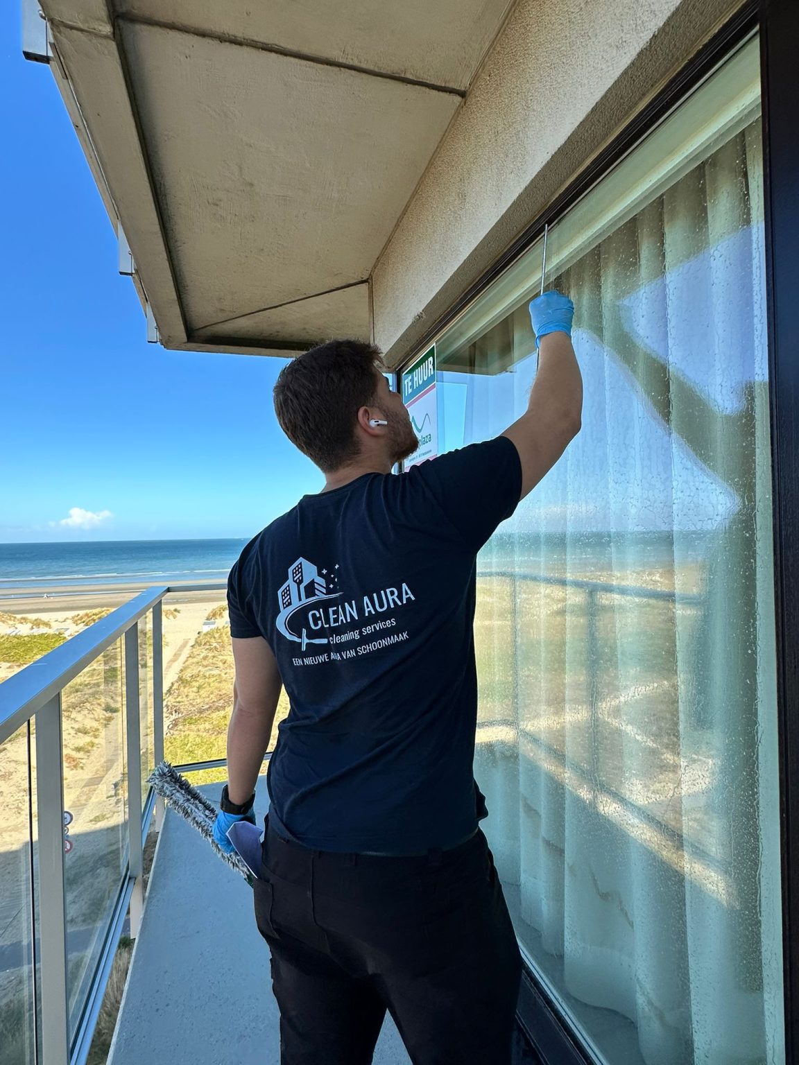 Clean Aura medewerker wast de ramen van een appartement aan de kust